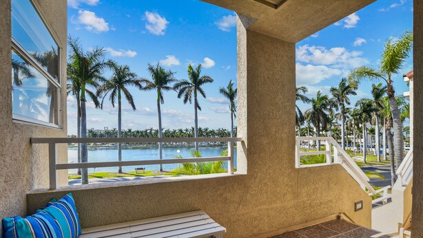 Ein Balkon mit einer Sitzbank und Blick auf Palmen und Wasser.