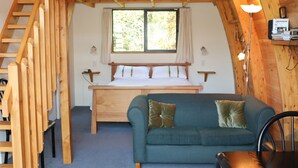 Une chambre de style « loft », avec un lit, un canapé bleu et un escalier en bois.