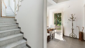 A modern interior with a marble staircase, a dining area with a table and chairs, and a coat rack. - Lovely home in Calci (PI) (Calci (PI))