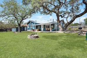 A house with a large yard, a covered porch, and a barbecue grill.