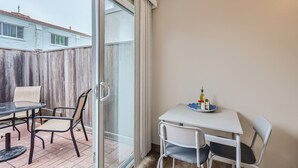 A balcony with a glass door, a table with chairs, and a small table with condiments. - OB Cottage w outdoor patio / 3 min to the beach   (San Diego)