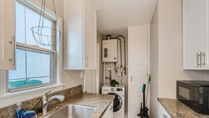 A compact kitchen with a stainless steel sink, a microwave, and a built-in washer and dryer. - OB Cottage w outdoor patio / 3 min to the beach   (San Diego)