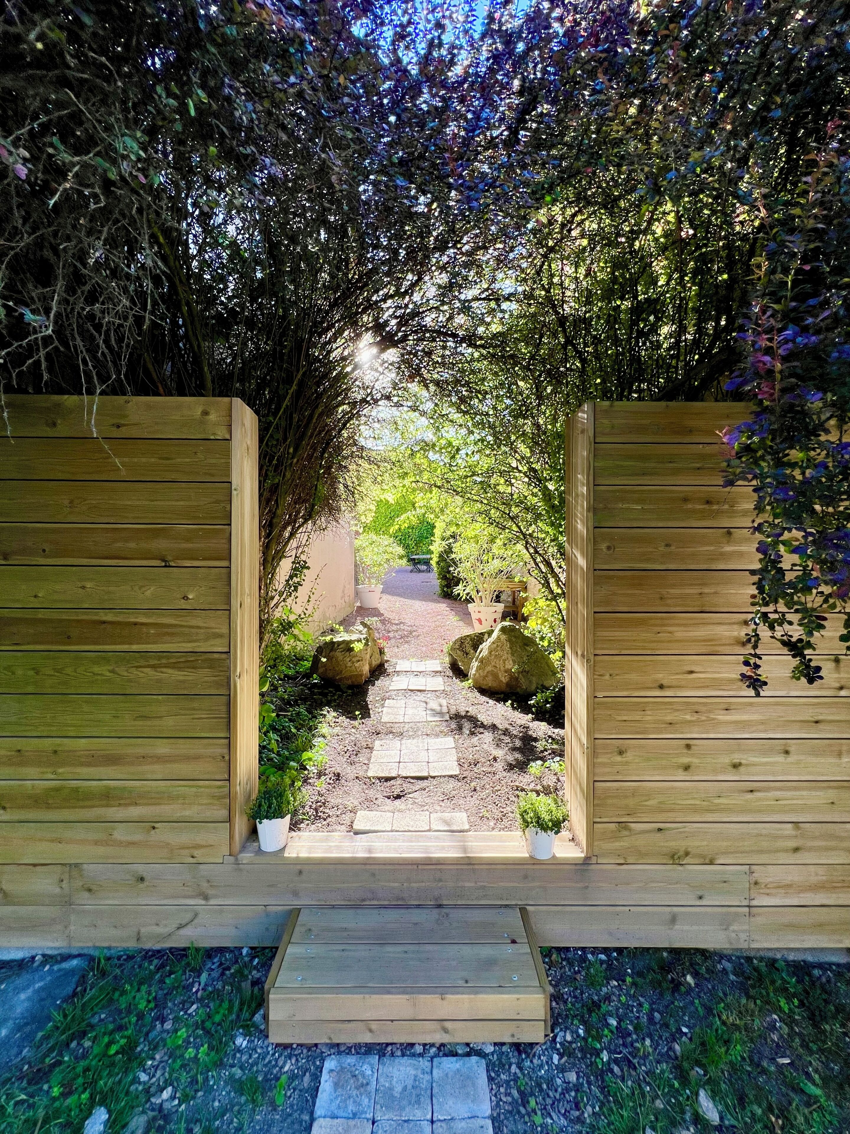 Una verja de madera con un sendero de piedra que atraviesa un jardín.