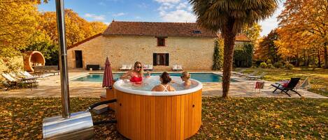 A hot tub in a garden with a stone building in the background.