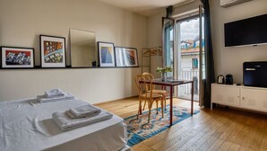 Ein Hotelzimmer mit Bett, Tisch mit Stühlen, Fernseher und Bildern an der Wand.