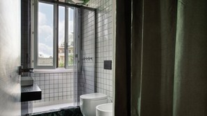 Ein Badezimmer mit Fenster, Dusche, Toilette und Waschbecken.