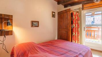 Une chambre à coucher avec un lit, une armoire en bois, une lampe de bureau et une fenêtre avec des rideaux.