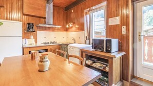 Un interno in legno con angolo cottura dotato di forno a microonde, macchina del caffè e tavolo da pranzo con sedie.
