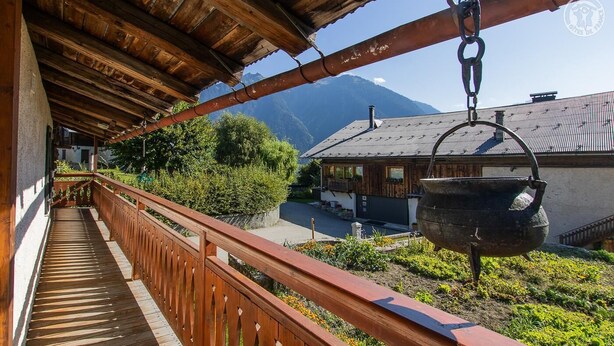 Un balcone in legno con vista su una montagna e un edificio tradizionale.