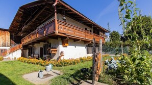 Tipico chalet in legno con balcone, immerso in un giardino curato con fiori gialli.
