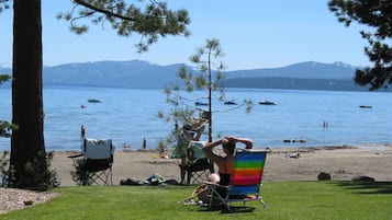 A beach with a grassy area, a colorful beach chair, and a tent.
