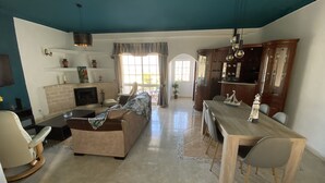 A spacious living room with a sofa, a dining table, and a kitchen area. - Vila Olival, Bbq, 2 Quartos, Espaço Exterior (Albufeira)