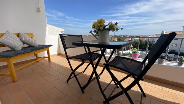 A balcony with a table and chairs, a potted plant, and a view of the city. - Vila Olival, Bbq, 2 Quartos, Espaço Exterior (Albufeira)