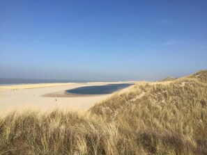 Una playa con dunas de arena y cielo despejado.