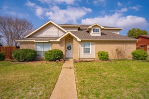 A two-story house with a front porch, a small garage, and a well-maintained lawn.