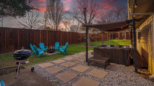 Een achtertuin met een barbecue, zitplaatsen buiten en een hottub.
