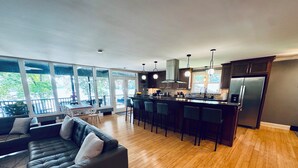 Una cocina moderna con una isla central, taburetes de bar y un refrigerador.