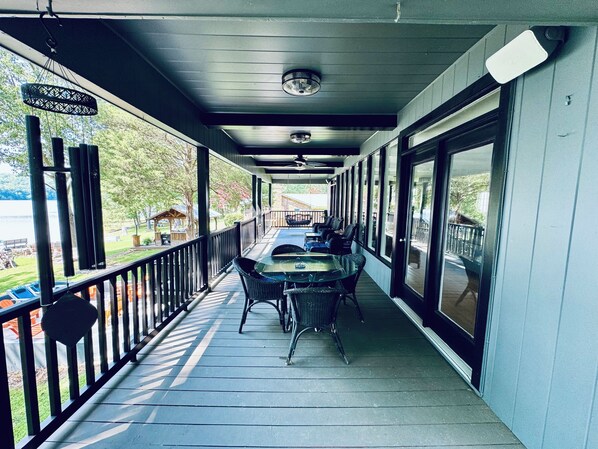 A covered outdoor area with a table and chairs, a railing, and large windows. - Lakefront with Million Dollar Views on HYCO Lake (Leasburg)