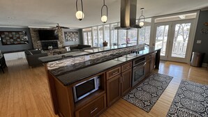 Una cocina moderna con una isla grande, armarios de madera y salpicadero de piedra.