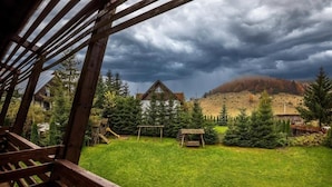 Una terraza de madera con vista a una casa y una colina.