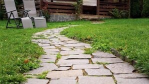 Un sendero de piedra que conduce a un pabellón de madera con zona de estar cubierta.