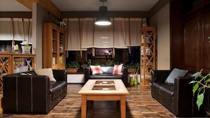 Una sala de estar acogedora con dos sofás de cuero, una mesa de centro de madera y un ventanal con cortinas.
