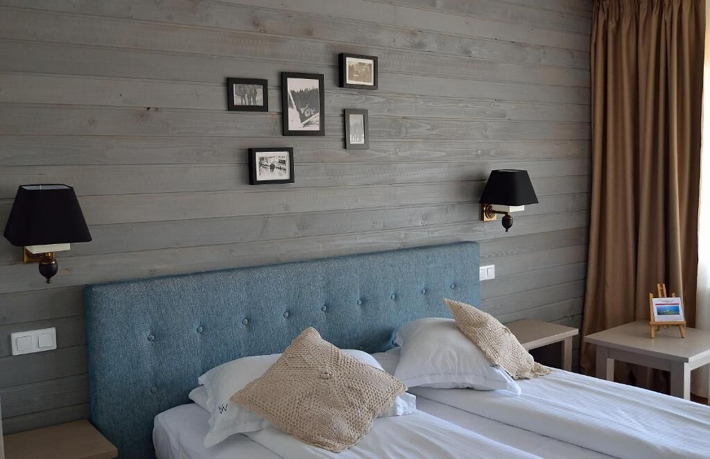 Une chambre d’hôtel avec une tête de lit bleue, du linge de lit blanc et des tableaux encadrés accrochés au mur.