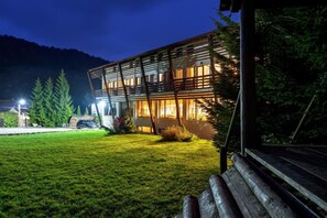 Un bâtiment moderne doté d’un toit en pente et de grandes fenêtres, entouré d’une pelouse bien entretenue et d’arbres.