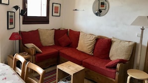 A cozy room with a red sofa, a small wooden table, and a window with a view.