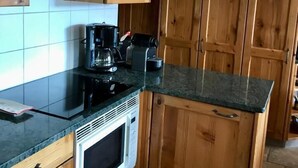 A kitchen with wooden cabinets, a black countertop, a stove, and a microwave.
