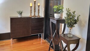 A room with a wooden floor, a dark brown dresser, a chair, and two potted plants. - Fully-furnished Modern Apartment / Executive Suite in Heart of Town
 (Big Timber)