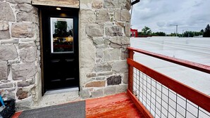 A stone building with a black door and the number 212. - Fully-furnished Modern Apartment / Executive Suite in Heart of Town
 (Big Timber)