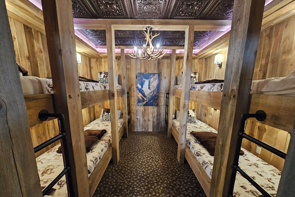 Una cabaña de madera con literas, una alfombra estampada y un candelabro.