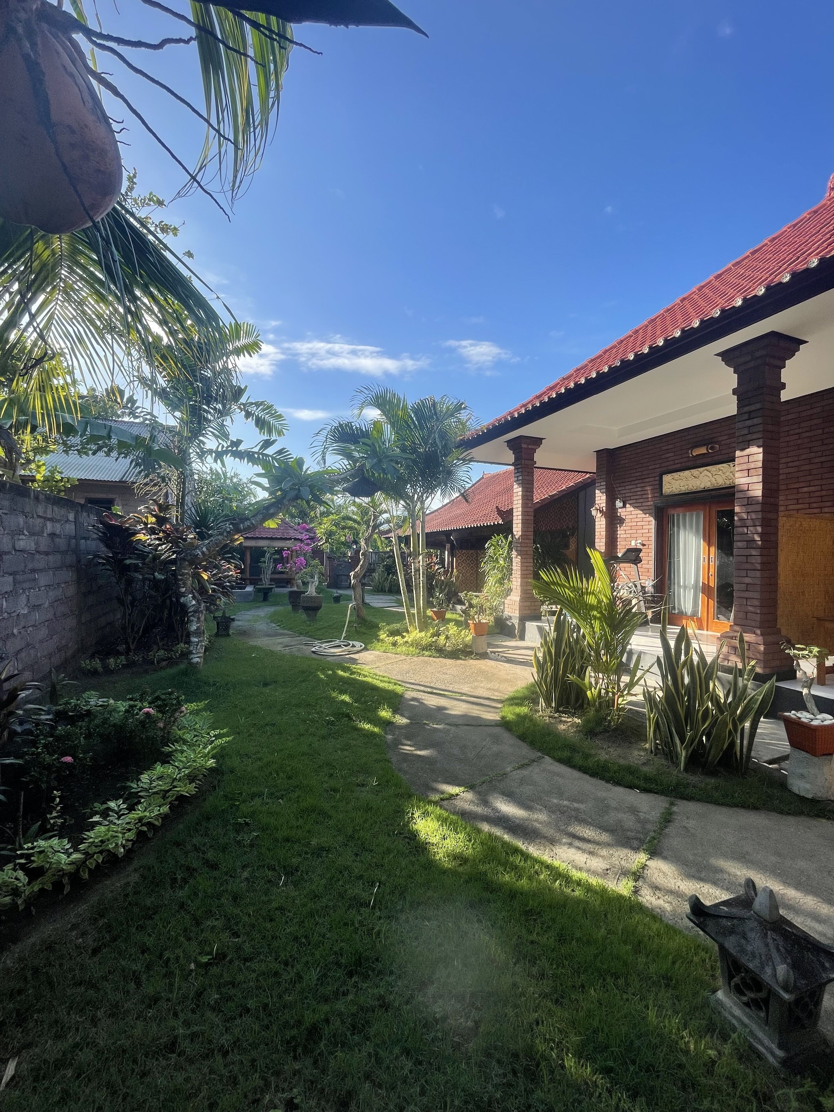 A courtyard with a brick building, palm trees, and a pathway.