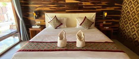 A large bed with a wooden headboard, two pillows, and a decorative runner.