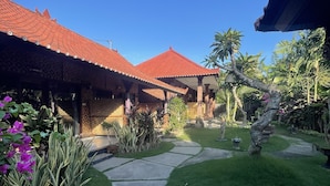 A courtyard with a pathway leading to a building with a red-tiled roof. - Tebu Menjangan (Pejarakan)