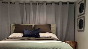 Een moderne slaapkamer met een net opgemaakt bed, een nachtkastje met handdoeken en een klein bankje.