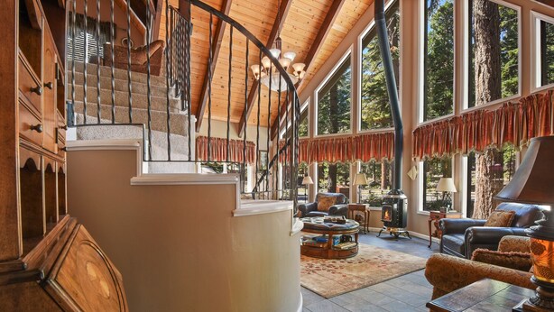 A spacious living area with a fireplace, leather furniture, and a large window overlooking a forested area.