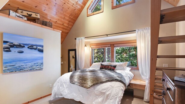 A bedroom with a bed, a painting, a window with curtains, and a wooden ceiling. - Lodgepole Lair - Remodeled, Walkable, Lake & Ski (Tahoe City)