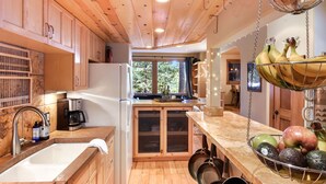 A kitchen with wooden cabinets, a refrigerator, a sink, and a window with a view of trees. - Lodgepole Lair - Remodeled, Walkable, Lake & Ski (Tahoe City)