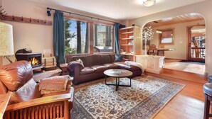 A cozy living room with a fireplace, leather sofa, and a coffee table. - Lodgepole Lair - Remodeled, Walkable, Lake & Ski (Tahoe City)