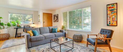 A modern living room with a grey sofa, a coffee table, and a patterned rug.