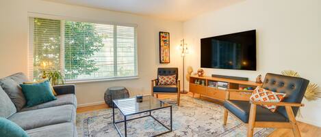 Una sala de estar moderna con sofá, sillón, mesa de centro y televisor.