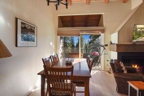 Un comedor con mesa y sillas de madera, chimenea y un telescopio.