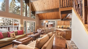 A spacious living area with a large sofa, a dining table, and a kitchen area with wooden cabinets and a bar.