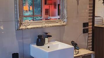 Une salle de bain avec un lavabo blanc, un grand miroir décoratif et un meuble-lavabo en bois.