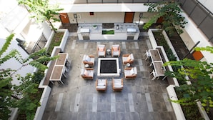 Ein Terrassenbereich im Freien mit Sitzmöbeln, einem Grillplatz und Pflanzgefäßen.