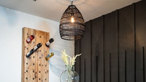 Ein Essbereich mit Holztisch und Stühlen, einer Pendelleuchte und einem an der Wand befestigten Weinkühler.