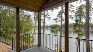 A wooden deck with a railing overlooking a lake, surrounded by trees. - Waterfront Luxury Tiny Home 360 North on Wilson Lake Close to Robert Trent Jones (Muscle Shoals)