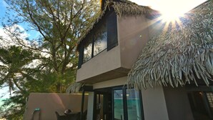 A two-story building with a thatched roof, large windows, and a view of the sea.